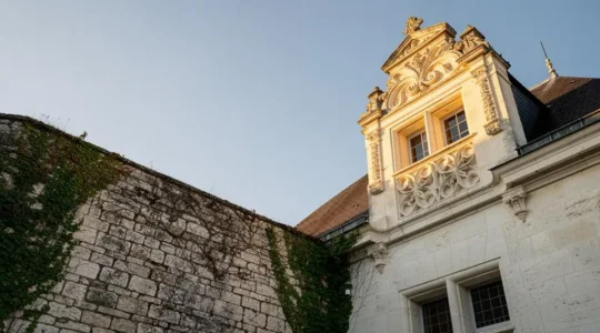 Facade d'un chateau en pierre de tuffeau du Val de Loire montrant plusieurs epoques architecturales superposees, avec lucarnes sculptees et jeux de lumiere rasante