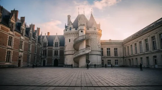 Vue d'ensemble de la cour du château de Blois au petit matin, révélant la juxtaposition des façades gothique, Renaissance et classique