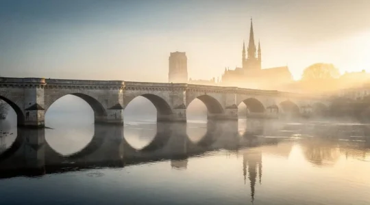 Vue symbolique de la Loire à l'aube à Orléans, avec un pont de pierre et la silhouette d'une flèche gothique en arrière-plan, évoquant la libération de 1429